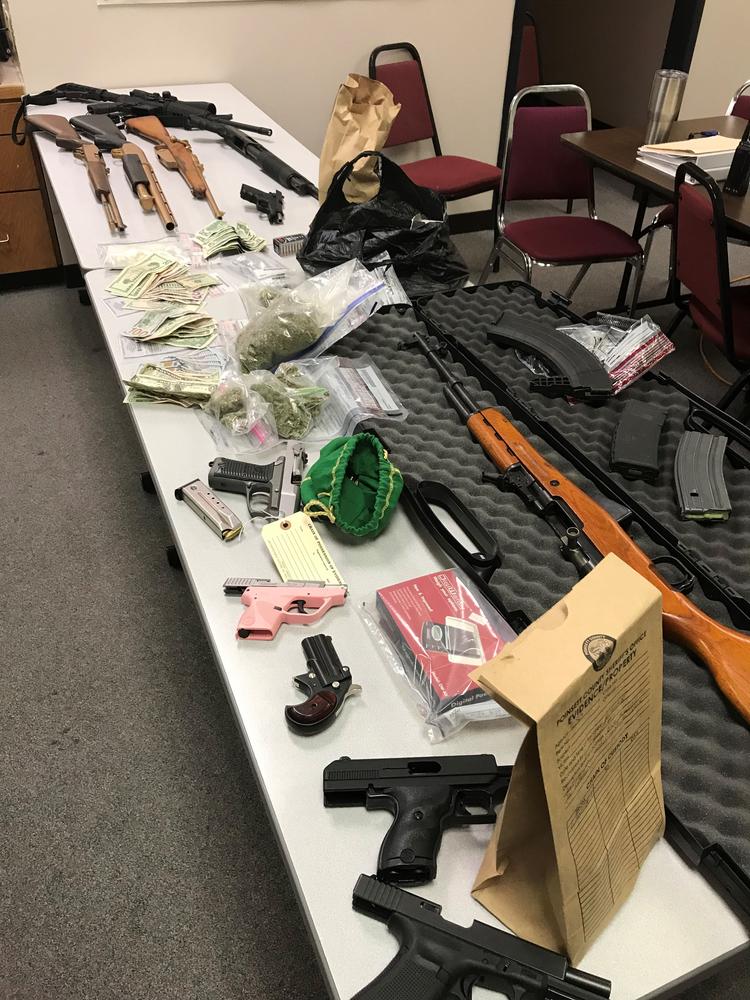 table covered in weapons and money and drugs